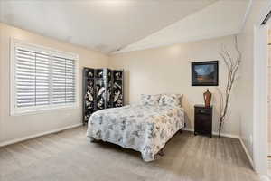 Bedroom featuring lofted ceiling and carpet flooring