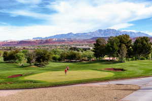 View of property's community with view of golf course, a mountain view, and a yard