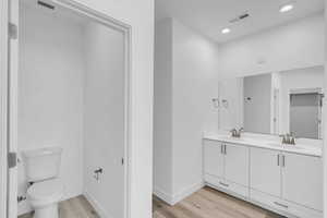 Bathroom featuring visible vents, a sink, toilet, and wood finished floors