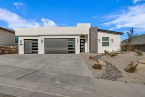 Contemporary house featuring concrete driveway, an attached garage, and stucco siding