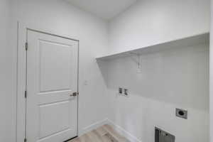 Clothes washing area featuring hookup for a washing machine, laundry area, baseboards, light wood finished floors, and electric dryer hookup