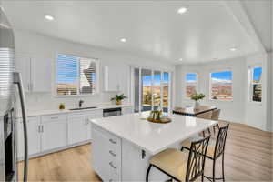 Kitchen with appliances with stainless steel finishes, light countertops, white cabinets, and a sink