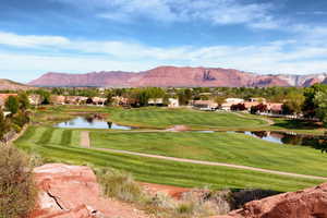 View of home's community with a lawn, golf course view, and a water and mountain view