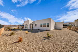 Rear view of property featuring fence and stucco siding