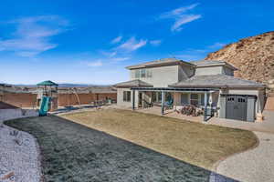 Back of house with a lawn, a patio, and a playground