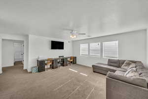 Living room featuring ceiling fan, light colored carpet, and a textured ceiling