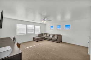 Living room featuring ceiling fan, carpet flooring, and a textured ceiling