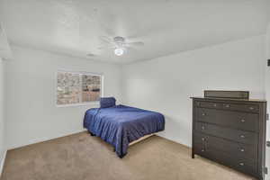 Carpeted bedroom with ceiling fan and a textured ceiling