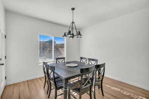 Dining room featuring an inviting chandelier, a textured ceiling, and light wood-type flooring