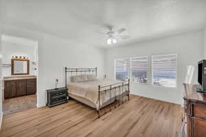 Bedroom with sink, ensuite bath, a textured ceiling, ceiling fan, and light hardwood / wood-style floors