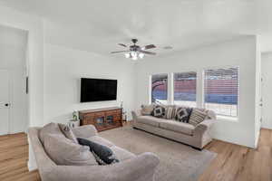 Living room featuring ceiling fan, light hardwood / wood-style flooring, and a textured ceiling