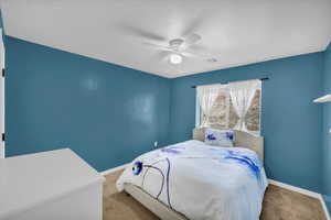 Carpeted bedroom featuring ceiling fan and a textured ceiling