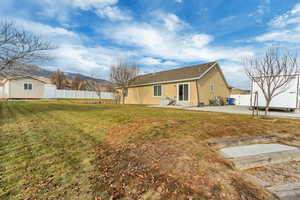 Rear view of property featuring a lawn and a patio area.