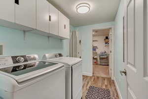 Laundry room featuring cabinets, independent washer and dryer, and light hardwood / wood-style flooring.