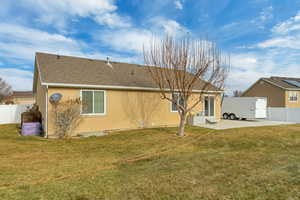 Back of house with a yard and a patio.