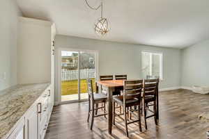 Dining space featuring an inviting chandelier and dark wood-type flooring.