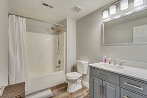 Full bathroom featuring shower / tub combo with curtain, hardwood / wood-style floors, vanity, and toilet.