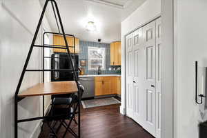 Kitchen featuring sink, tasteful backsplash, hanging light fixtures, dark hardwood / wood-style flooring, and dishwasher