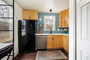 Kitchen featuring dark wood-type flooring, sink, black refrigerator, dishwasher, and pendant lighting