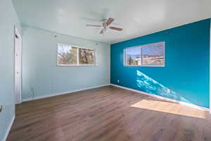 Empty room featuring dark wood-type flooring and ceiling fan