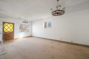 Unfurnished dining area with carpet flooring, a chandelier, and a textured ceiling