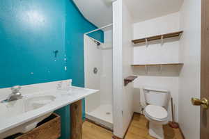 Bathroom with a shower, sink, hardwood / wood-style floors, and toilet