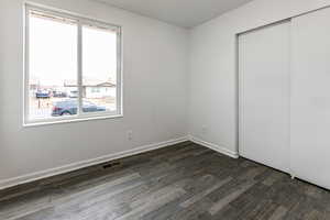 Unfurnished bedroom with dark wood-type flooring and a closet