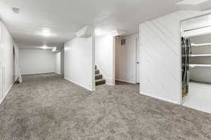 Basement featuring refrigerator, carpet floors, and a textured ceiling