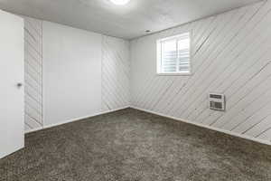 Carpeted spare room featuring a wall unit AC, wooden walls, and a textured ceiling