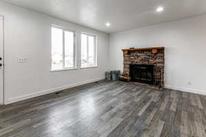 Living room with a stone fireplace and dark hardwood / wood-style floors