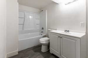 Full bathroom featuring wood-type flooring, vanity,  shower combination, toilet, and a textured ceiling