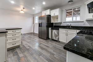 Kitchen featuring stainless steel appliances, white cabinetry, dark hardwood / wood-style floors, and decorative backsplash