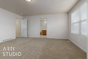 Unfurnished bedroom featuring light carpet and connected bathroom