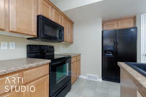 Kitchen featuring light tile patterned floors and black appliances