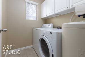 Clothes washing area featuring washing machine and dryer and cabinets