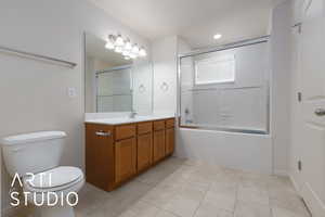 Full bathroom with vanity, tile patterned floors, shower / bath combination with glass door, and toilet