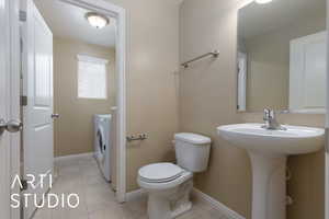 Bathroom with tile patterned flooring, washer / dryer, and toilet