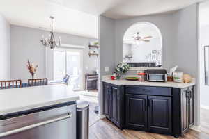 Kitchen with ceiling fan with notable chandelier, pendant lighting, stainless steel dishwasher, and light hardwood / wood-style floors