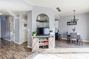 Kitchen featuring pendant lighting, hardwood / wood-style floors, lofted ceiling, and white cabinets