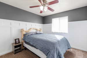 Carpeted bedroom featuring ceiling fan and a textured ceiling