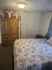 Bedroom featuring a closet, dark carpet, and a textured ceiling