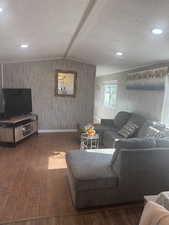 Living room featuring lofted ceiling with beams, dark hardwood / wood-style floors, and a textured ceiling