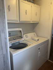 Washroom with cabinets, dark wood-type flooring, and washer and clothes dryer