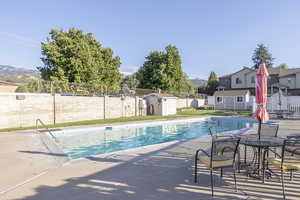 View of swimming pool with a mountain view, a patio area, and a storage shed