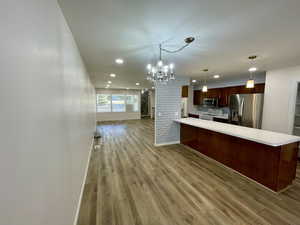 Kitchen featuring pendant lighting, tasteful backsplash, kitchen peninsula, stainless steel appliances, and light wood-type flooring