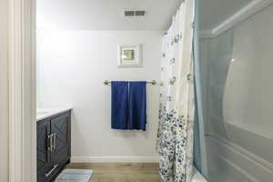 Bathroom featuring vanity, wood-type flooring, shower / tub combo, and a textured ceiling