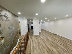 Basement with stainless steel fridge and light hardwood / wood-style floors