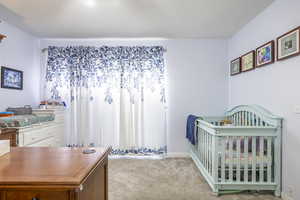 Bedroom with light carpet and a crib