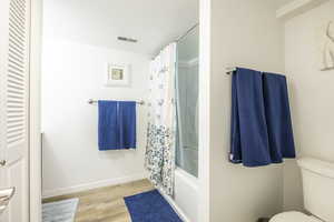 Bathroom featuring hardwood / wood-style flooring, shower / bath combination with curtain, and toilet