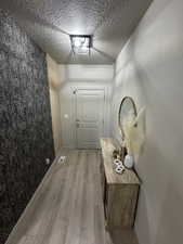 Doorway featuring a textured ceiling and light wood-type flooring